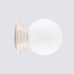 Kinkiet Zori 1xG9 IP44 w kolorze beżowym z okrągłą, matową kloszem. Ujęcie frontalne, produkt stojący na dekoracyjnej, falistej podstawie. Biały klosz kontrastuje z beżową bazą, tworząc elegancki wygląd.