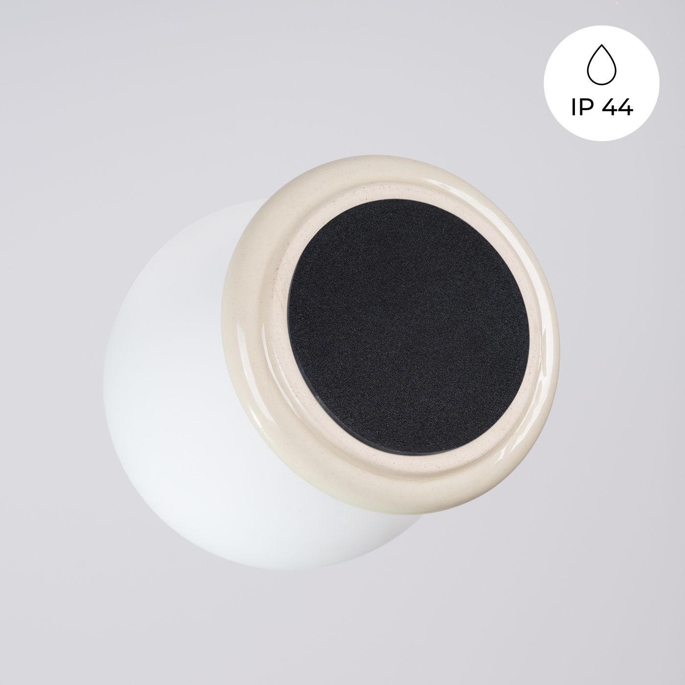 Beżowy kinkiet Zori 1xG9 IP44, z zaokrągloną, matową oprawą i czarnym, teksturowanym elementem na górze. Produkt umieszczony na neutralnym tle, w pozycji wiszącej, idealny do wnętrz i miejsc narażonych na wilgoć.