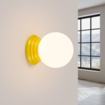 Kinkiet Zori 1xG9 IP44 w kolorze żółtym, z okrągłą, białą oprawą. Montowany na ścianie, z widocznym żłobionym uchwytem. Tło neutralne, z oknem w tle, co sugeruje aranżację wnętrza. Idealny do oświetlenia przestrzeni.
