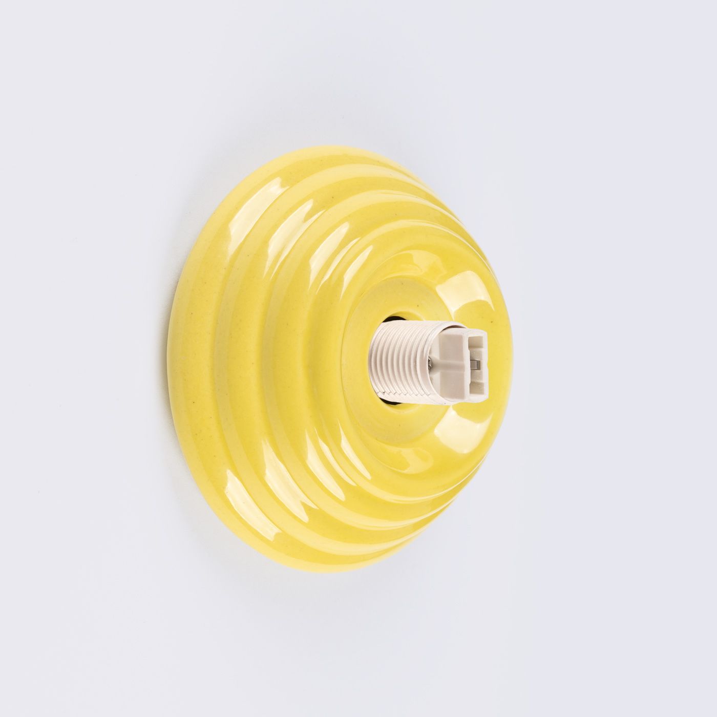 Kinkiet Zori 1xG9 IP44 w kolorze żółtym, o okrągłej, falistej podstawie. Widoczny gwint do żarówki G9 w centrum. Produkt zawieszony na białym tle, gotowy do montażu.