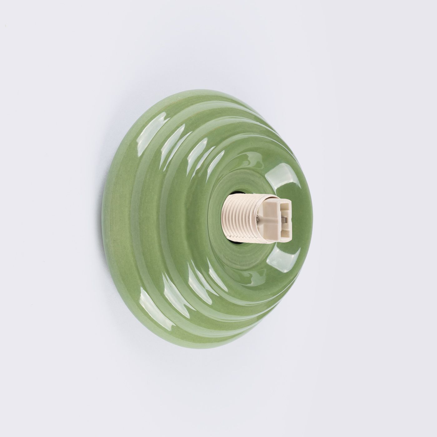 Zielony kinkiet Zori z ceramicznym, falistym kloszem, z widocznym gniazdem na żarówkę G9. Produkt ma matową powierzchnię i jest montowany na ścianie. Klosz o okrągłym kształcie, stworzony z myślą o zastosowaniach wewnętrznych i na zewnątrz (IP44).