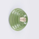 Zielony kinkiet Zori z ceramicznym, falistym kloszem, z widocznym gniazdem na żarówkę G9. Produkt ma matową powierzchnię i jest montowany na ścianie. Klosz o okrągłym kształcie, stworzony z myślą o zastosowaniach wewnętrznych i na zewnątrz (IP44).