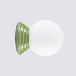 Zielony kinkiet Zori z podstawą w falistym kształcie i białą, okrągłą szklaną kopułą. Produkt ustawiony na płaskiej powierzchni, z widoczną strukturą podstawy. Idealny do wnętrz, spełnia wymogi IP44.