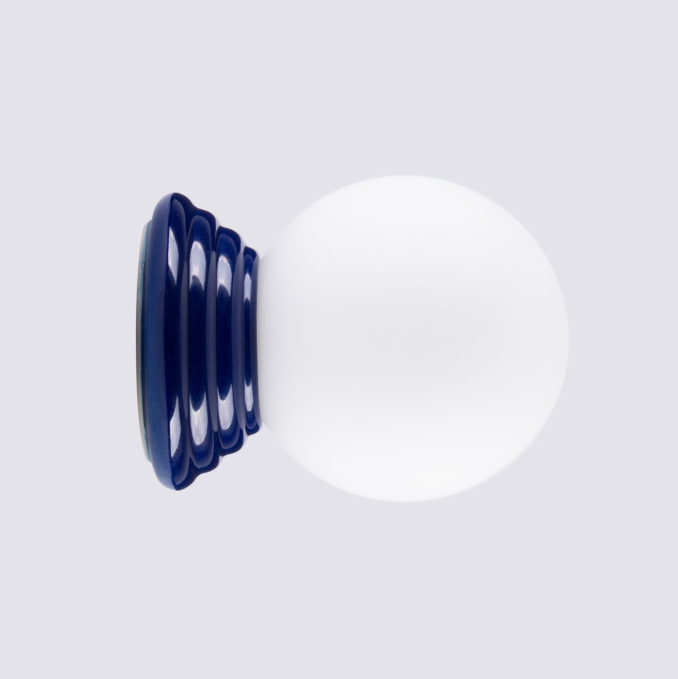 Kinkiet Zori 1xG9 IP44 w kolorze ultramaryny z okrągłą, białą kloszem na eleganckiej, falistej podstawie. Ujęcie frontalne, produkt stojący na jednolitym tle. Idealny do wnętrz oraz na zewnątrz.