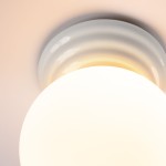 Biała lampa sufitowa Zori z oprawą w kształcie okrągłej, matowej klosza. Ujęcie z dołu, ukazujące detale górnej części oprawy z delikatnymi żłobieniami. Produkt przeznaczony do użytku w pomieszczeniach, z klasą odporności IP44.
