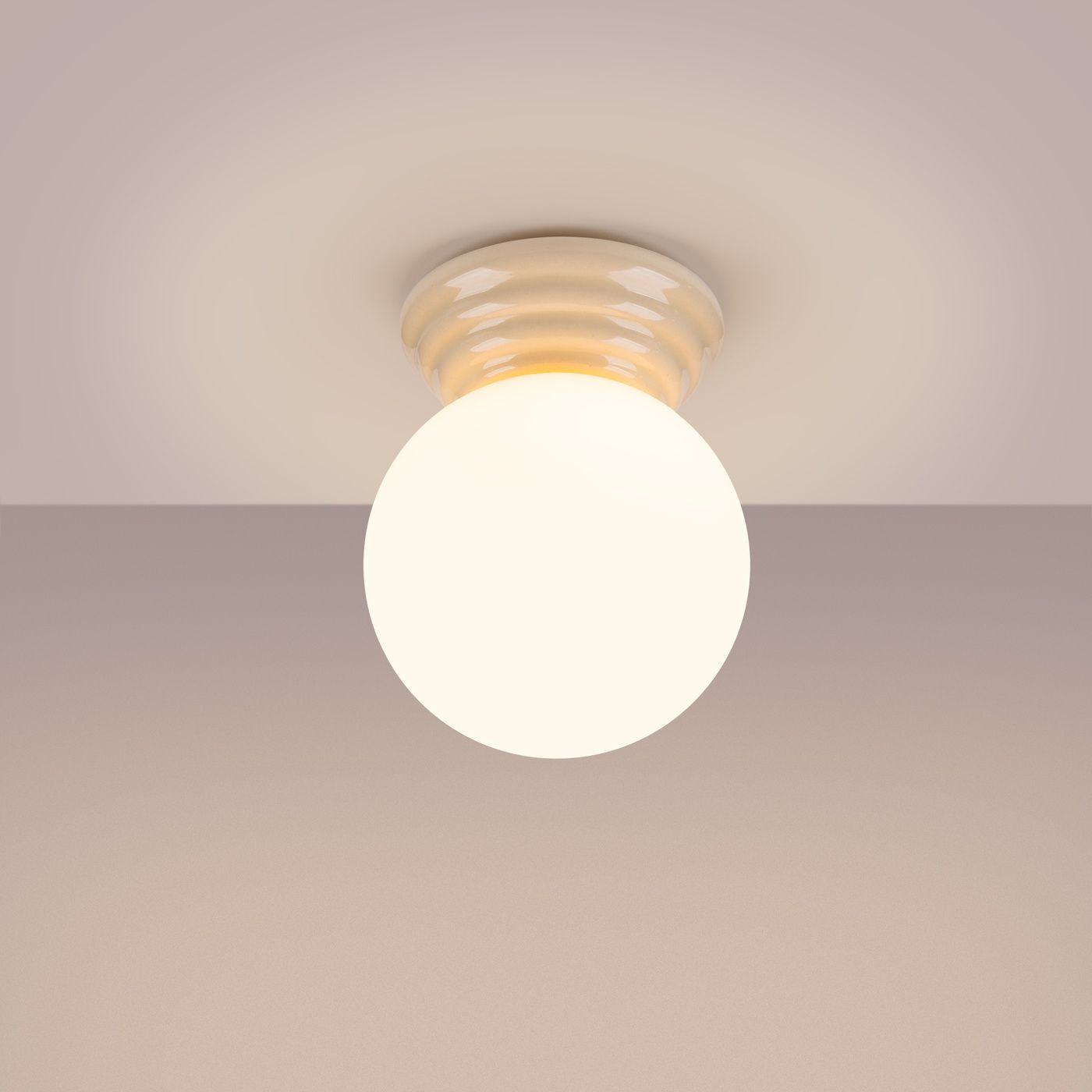 Beżowa lampa sufitowa Zori z pojedynczym źródłem światła G9, o okrągłym kształcie. Zainstalowana na gładkim, okrągłym mocowaniu. Delikatne światło emitowane przez mlecznobiałą kulę. Produkt przeznaczony do użytku wewnętrznego, klasyfikacja IP44.
