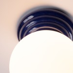 Lampa sufitowa Zori w kolorze ultramaryny z podstawa w kształcie okręgu, z gładką, błyszczącą powierzchnią. Źródło światła G9 umieszczone w centralnej, białej, okrągłej kloszy. Ujęcie z góry, ukazujące detale podstawy i klosza.