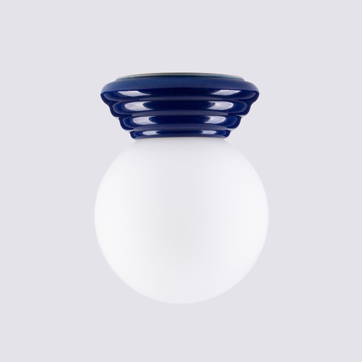 Lampa sufitowa Zori 1xG9 IP44 w kolorze ultramaryny, z okrągłym, mlecznym kloszem i falistym, niebieskim uchwytem. Produkt montowany sufitowo, widoczny z góry, idealny do wnętrz.