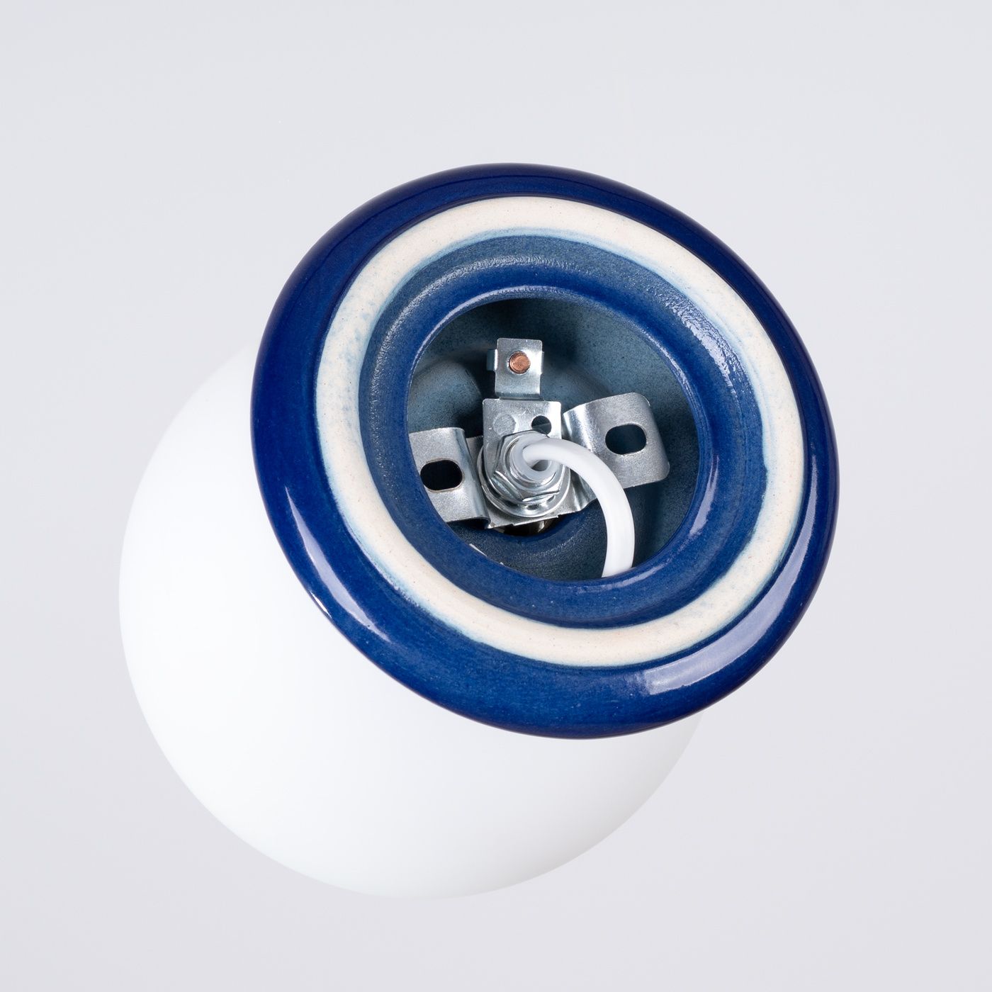 Lampa sufitowa Zori w kolorze ultramaryny z ceramicznym kloszem. Widok z góry, ukazujący gniazdo na żarówkę G9 oraz metalowe mocowania. Gładka, biała powierzchnia klosza z błyszczącym niebieskim wykończeniem. Idealna do wnętrz o nowoczesnym stylu.