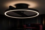 Lampa sufitowa Tivoli 1xLED 24W CCT w kolorze czarnym, o okrągłym kształcie z delikatnym, podświetlonym pierścieniem. Ujęcie z dołu, z widocznym montażem do sufitu oraz fragmentem tła w ciemnych odcieniach.
