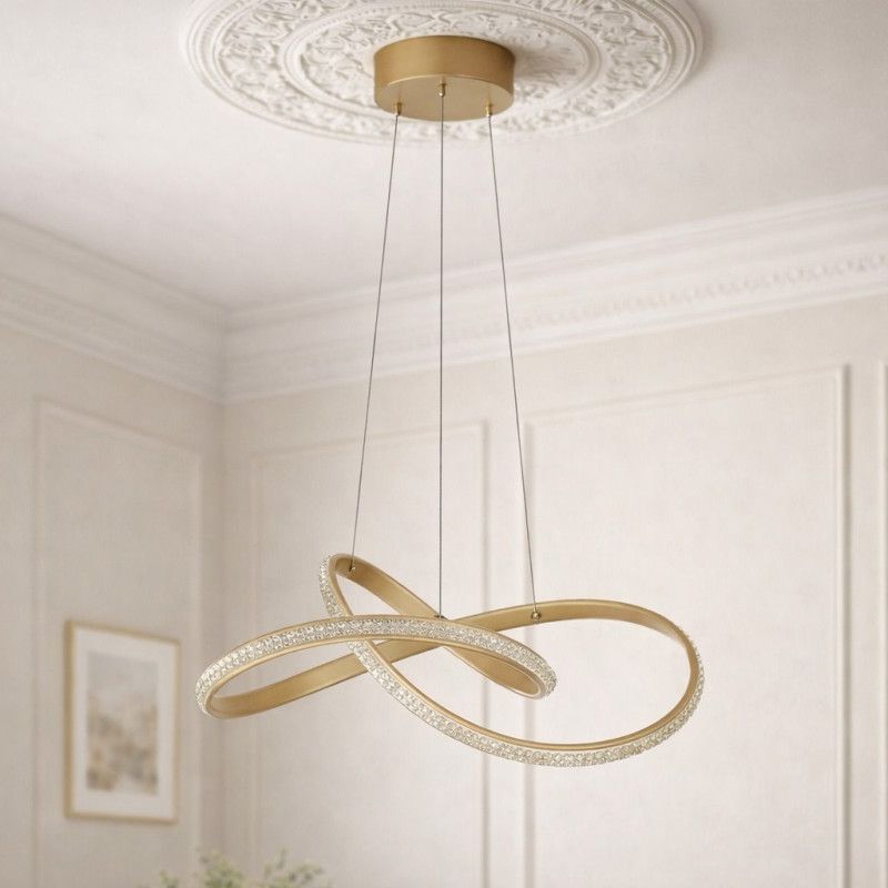 Lampa wisząca Fondi 1xLED 40W CCT w kolorze złotym, z dwiema splecionymi obręczami, zdobionymi przezroczystymi elementami. Zawieszona na cienkich linkach, montowana sufitowo, w eleganckim wnętrzu.