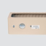 Rigata kinkiet 1xE27 w kolorze taupe, prostokątny kształt z teksturowaną krawędzią. Widoczny otwór na mocowanie oraz miejsce na żarówkę. Na metalowej powierzchni znajdują się oznaczenia techniczne. Tło jasnoszare.