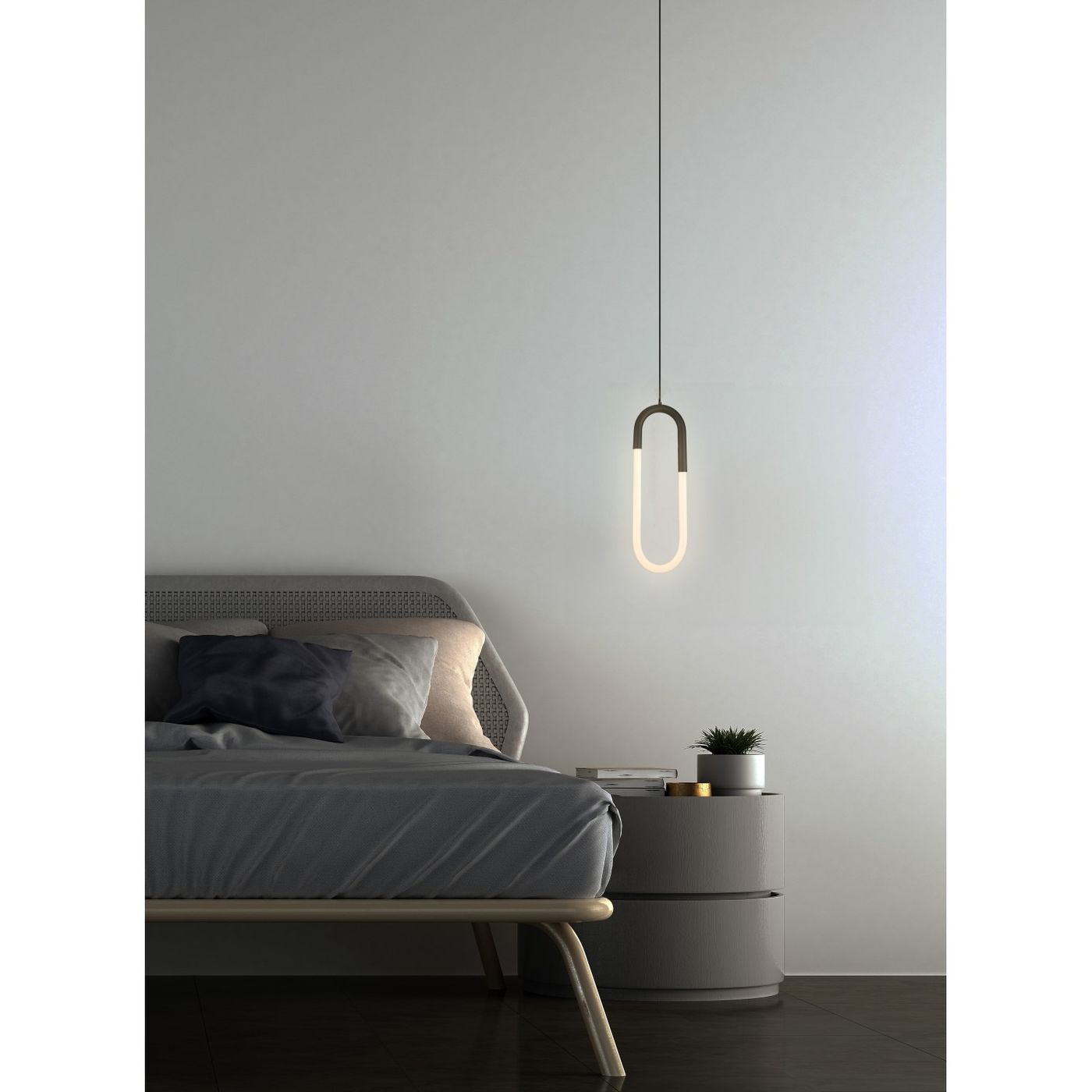Lampa wisząca LED Nexus 9W w czarnej obudowie o kształcie elipsy, zawieszona nad łóżkiem w sypialni. Światło emitowane przez lampę ma ciepły odcień, a tło jest jasne, minimalistyczne, z meblami w neutralnych kolorach.