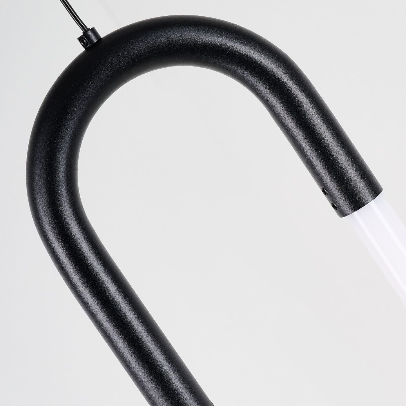 Lampa wisząca LED Nexus 9W w kolorze czarnym, z charakterystycznym, zakrzywionym kształtem. Widoczna metalowa konstrukcja z matowym wykończeniem oraz przezroczysty element świetlny. Produkt zawieszony na cienkim przewodzie, na jednolitym tle.