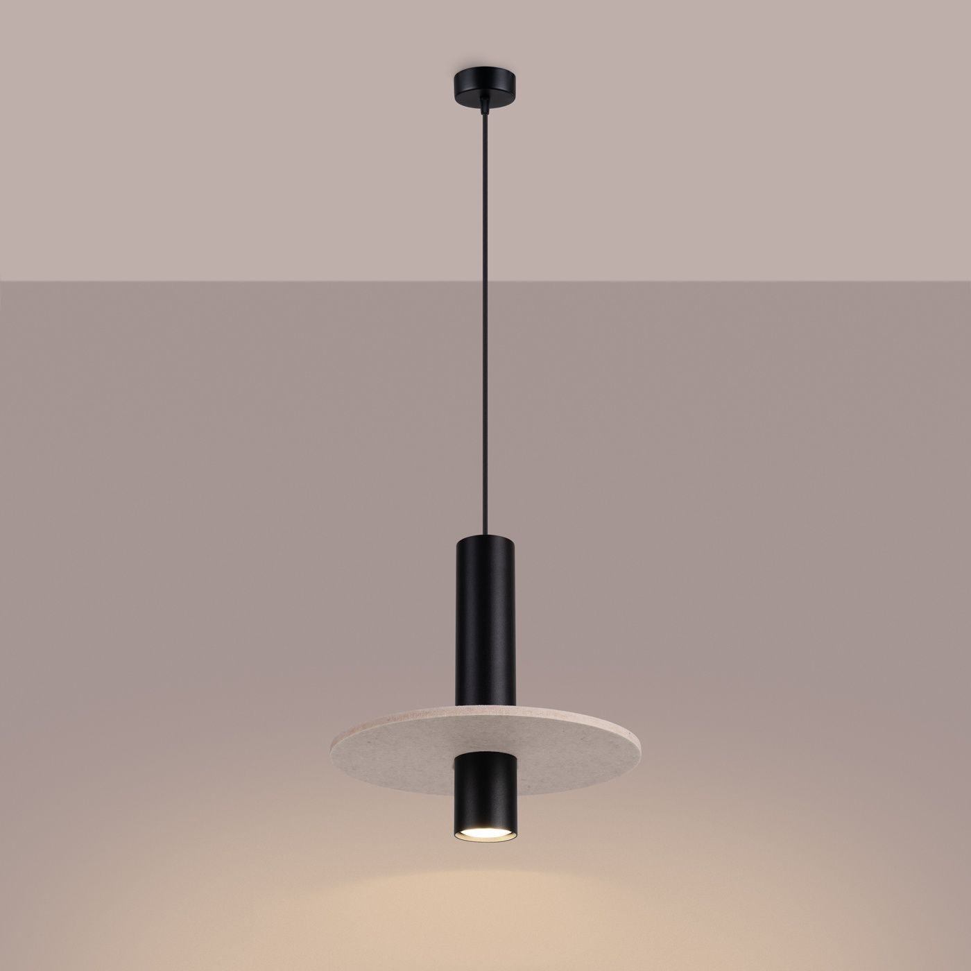 Lampa wisząca Pelta 1xGU10 w kolorze czarnym i beżowym. Okrągła, beżowa podsufitka z metalowym, czarnym uchwytem. Produkt zawieszony na cienkim przewodzie, z widocznym miejscem na żarówkę. Prosty, nowoczesny design.