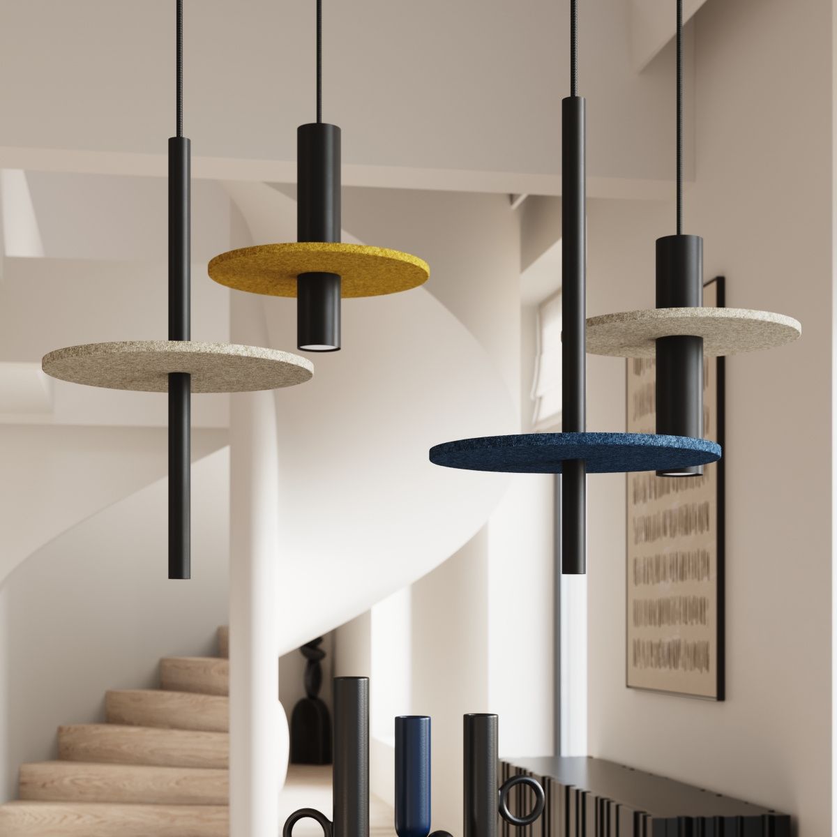 Lampa wisząca Pelta z jedną oprawą GU10, z czarnymi metalowymi elementami i okrągłymi, kolorowymi kloszami w beżu, żółci i niebieskim. Wisi w nowoczesnym wnętrzu, na tle schodów i jasnych ścian.