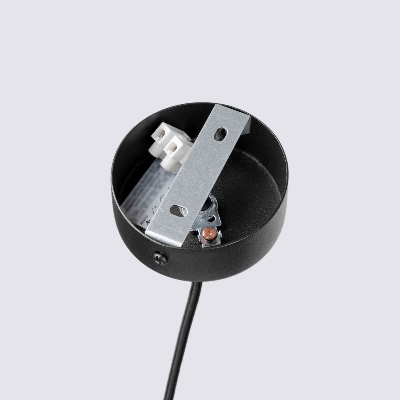 Czarna lampa wisząca Pelta 1xGU10, widok od góry. Metalowy klosz z mocowaniem i przewodem w kolorze czarnym. W środku elementy montażowe i złącza elektryczne. Prosta konstrukcja, idealna do nowoczesnych wnętrz.