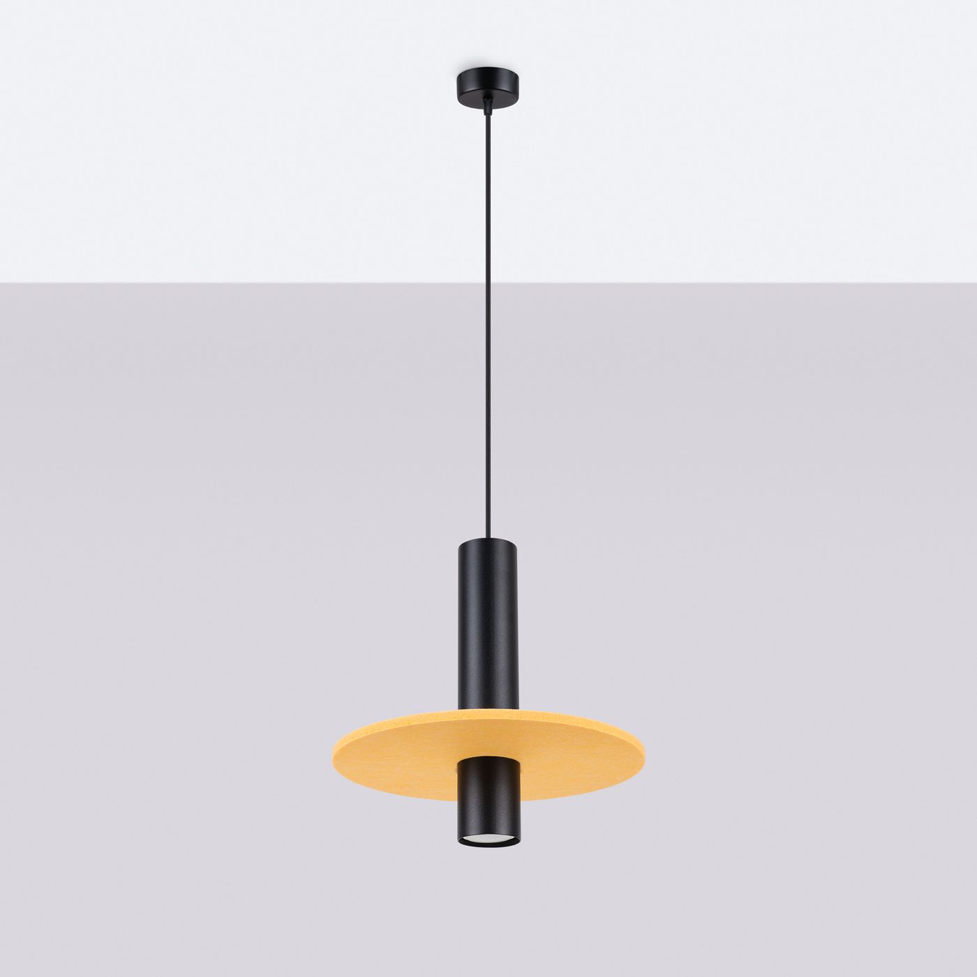 Lampa wisząca Pelta z jedną oprawą GU10, w kolorze czarnym z żółtym kloszem w kształcie talerza. Produkt zawieszony na cienkim, czarnym przewodzie, zmontowany w pozycji wiszącej, na jednolitym tle.