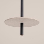 Lampa wisząca Feltro w kolorze czarnym i beżowym, z okrągłym kloszem z filcu na metalowej rurze. Ujęcie z dołu, pokazujące zbliżenie na detal lampy i źródło światła. Tło w stonowanym odcieniu.