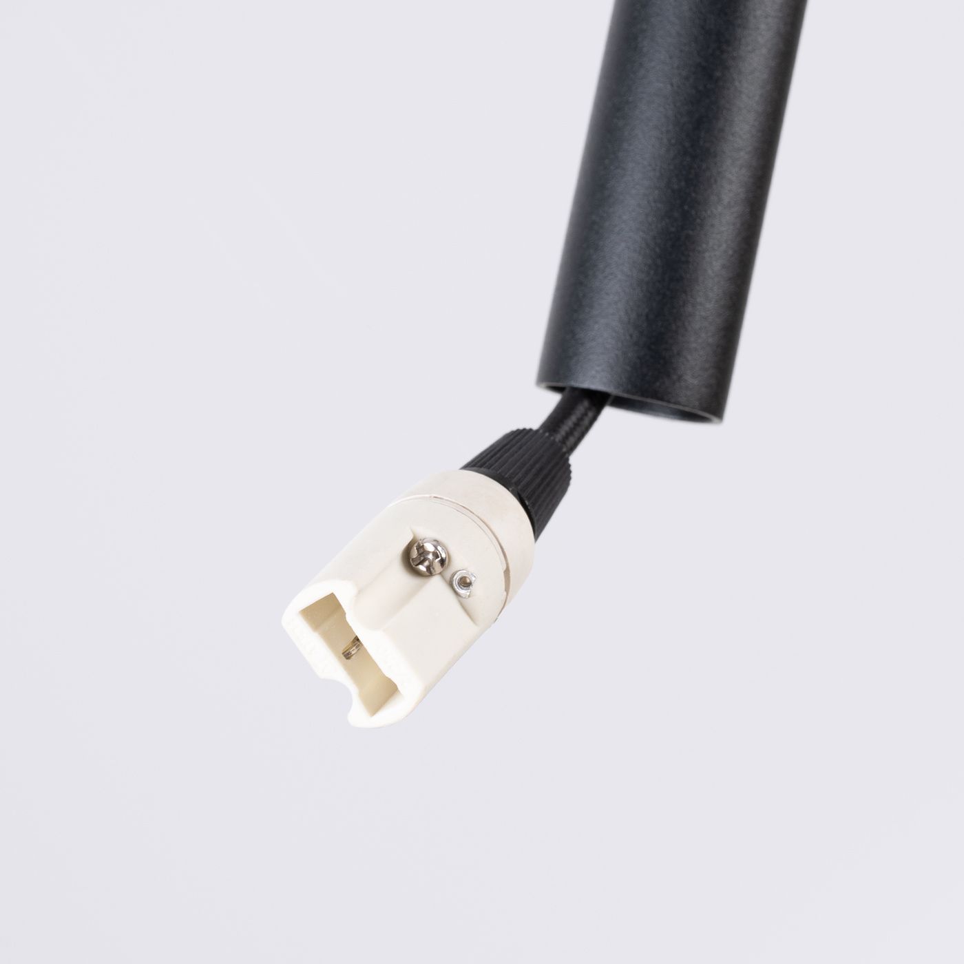 Zbliżenie na czarny kabel lampy wiszącej Feltro z gniazdem G9. Widoczna biała wtyczka z metalowym mocowaniem. Tło jednolite, neutralne.