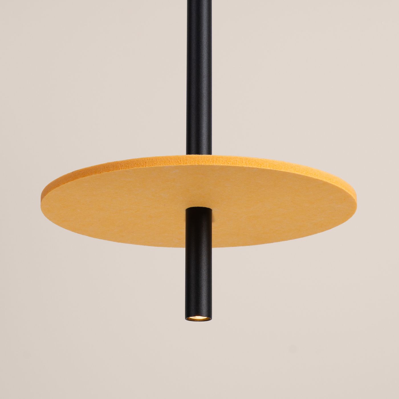 Lampa wisząca Feltro 1xG9 w kolorze czarnym i żółtym. Okrągła, żółta podsufitka z materiału, z centralnym czarnym trzonkiem. Produkt zawieszony pod kątem, na jednolitym tle. Brak widocznych napisów lub logo.