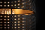Czarna lampa sufitowa Malavi z pięcioma miejscami na żarówki E27. Widziana z bliska, ukazuje perforowaną, teksturowaną konstrukcję klosza, przez którą przebija ciepłe światło. Wnętrze klosza w kolorze złotym dodaje elegancji.