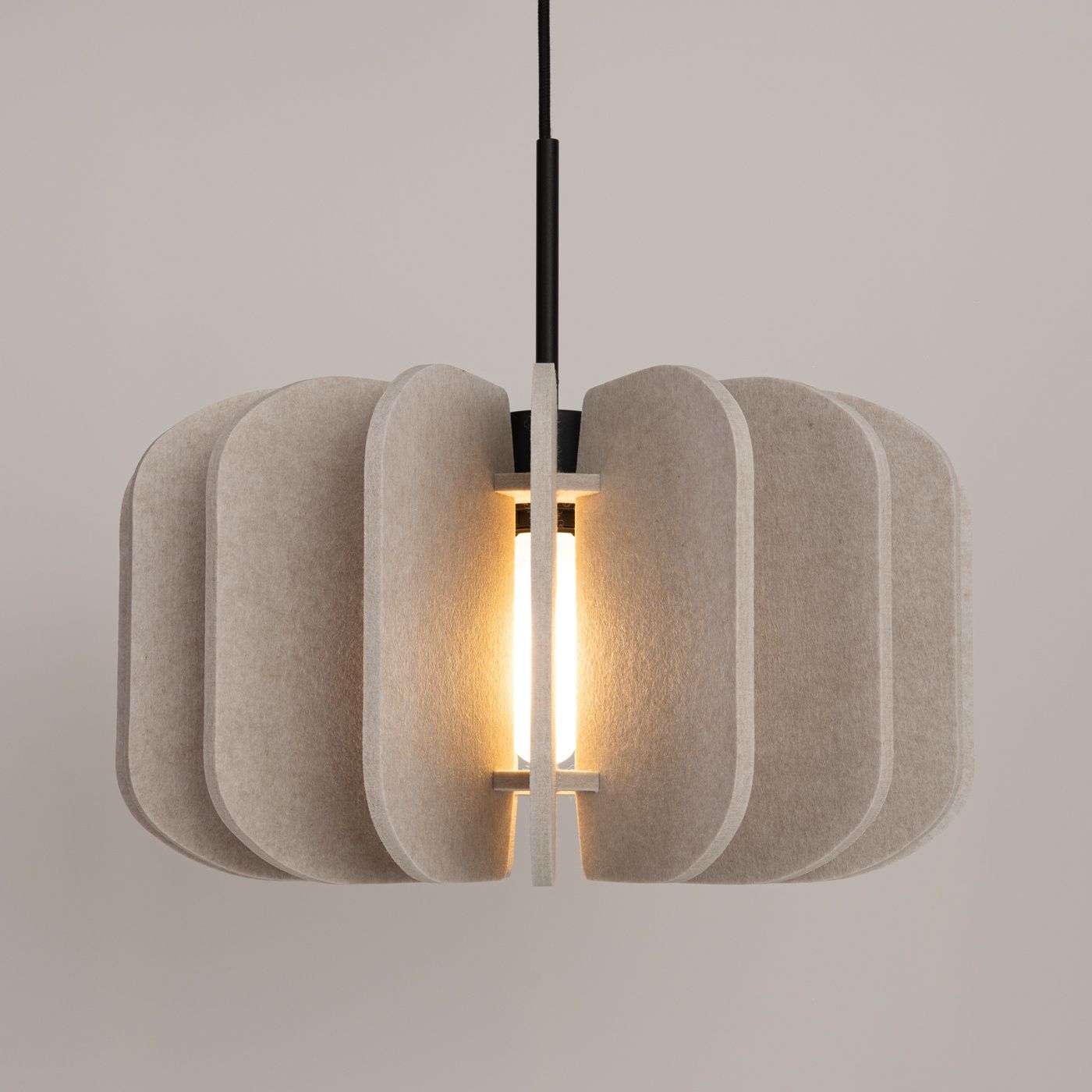 Lampa wisząca Mula D45 z czarnym przewodem, posiada beżowy klosz z teksturowanego materiału, o okrągłym kształcie z podziałem na segmenty. Światło wydobywa się z centralnej żarówki E27, tworząc przytulną atmosferę.