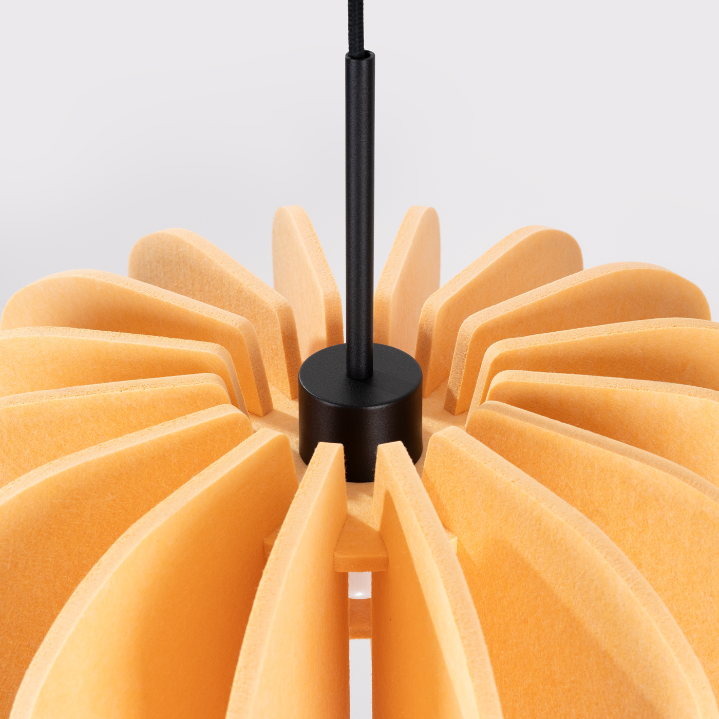 Lampa wisząca Mula D45 z mocowaniem w kolorze czarnym, posiada klosz w kształcie kwiatowym w odcieniu żółtym. Widoczne są wyraźne, faliste elementy klosza oraz czarny kabel. Produkt zamontowany w centralnym punkcie ujęcia.