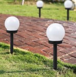 Lampa solarna ogrodowa Ballo D10/H34 z białą, okrągłą głowicą, umieszczona na czarnym stelażu. Widoczna na trawniku obok ścieżki z cegły. Wysokość lampy wynosi 34 cm, średnica głowicy 10 cm.