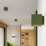 Kinkiet Quad Beton 1xG9 w kolorze zielonej oliwki, wykonany z betonu, w kształcie kwadratu. Zainstalowany na ścianie, emitujący światło w kierunku do góry, w nowoczesnym wnętrzu z drewnianymi akcentami.
