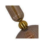 Lampa wisząca Piega D30 z jednym gniazdem E27, wykonana z dymionego szkła i elementów w kolorze patyny. Widoczne detale to żłobienia na szkle oraz złoty, kulisty mocownik. Ujęcie z boku, ukazujące połączenie elementów.