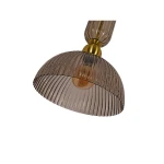 Lampa wisząca Piega D30 z kloszem w kolorze dymionym, wykonana z tworzywa, z metalowym wykończeniem w kolorze patyny. Klosz ma delikatne żłobienia i okrągły kształt, montowana na suficie, z widoczną żarówką E27.