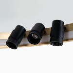 Lampa sufitowa Serafino D82 z siedmioma czarnymi oprawami LED 43W, zamontowana na złotej konstrukcji. Ujęcie z bliska, pokazujące detale mocowania i źródeł światła. Tło jasne, minimalistyczne.