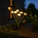 Lampa solarna ogrodowa w kształcie grzybków, z sześcioma przezroczystymi kloszami LED, wbijana w ziemię. Zielone metalowe nóżki, podświetlona w nocy, umiejscowiona na tle ściany budynku i ścieżki ogrodowej.