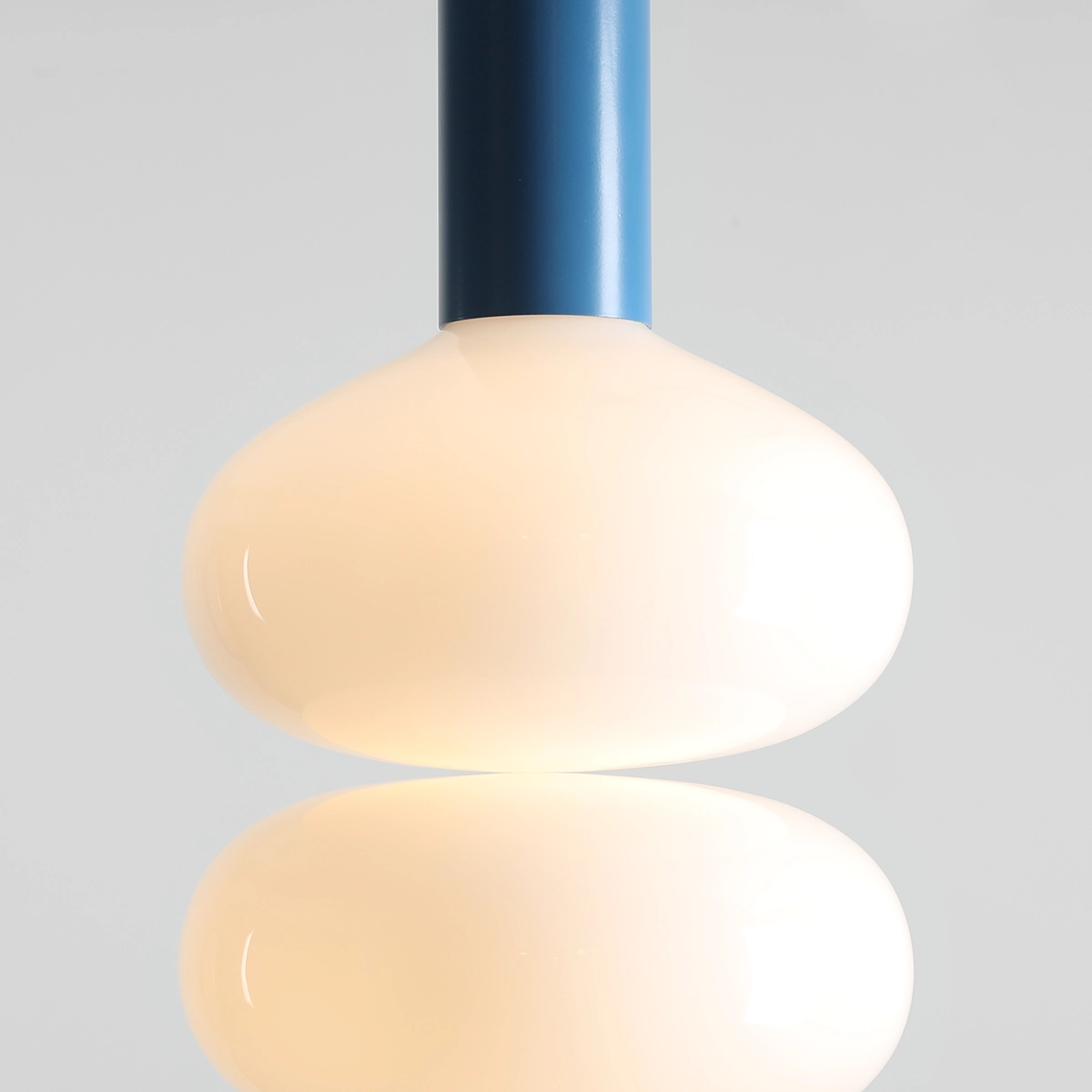 Lampa wisząca Flo Sky D26 z oprawą w kolorze niebieskim i kulistym kloszem z mlecznego szkła. Ujęcie z bliska, pokazujące gładką fakturę klosza i mocowanie. Idealna do nowoczesnych wnętrz.