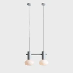 Lampa wisząca Flo Grey z dwoma oprawami na żarówki E14. Konstrukcja w kolorze szarym z metalowym stelażem i dwoma okrągłymi, mlecznymi kloszami. Zawieszona na dwóch cienkich linkach, w prostej, nowoczesnej formie, idealna do wnętrz.