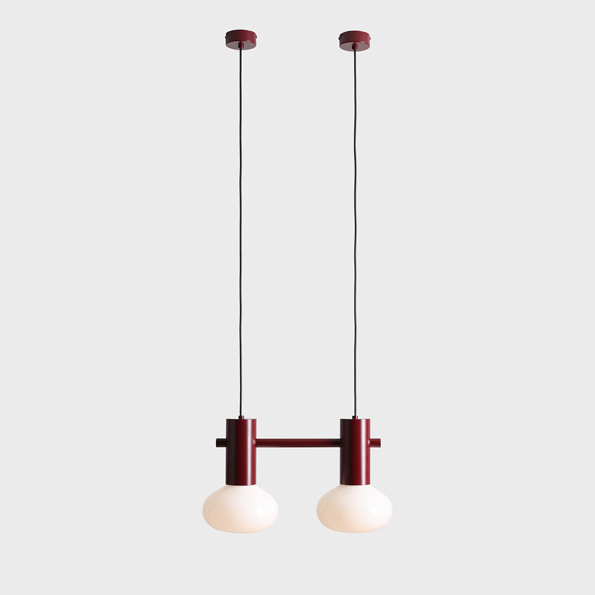 Lampa wisząca Flo Ruby z dwoma okrągłymi kloszami w kolorze białym, zamocowana na czerwono-różowej podstawie. Uchwyt w formie prostokąta z dwoma metalowymi elementami, zawieszona na dwóch czarnych przewodach. Tło jasnoszare.