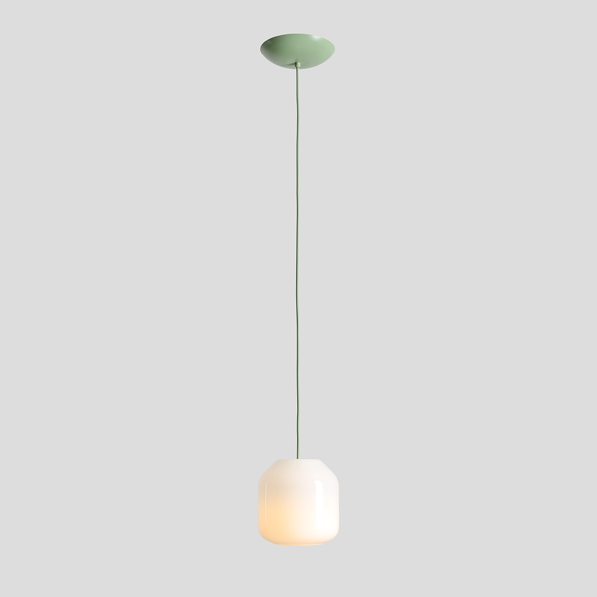 Lampa wisząca Flask Sage D18 w kolorze szałwii, z białym kloszem o kształcie heksagonalnym, zawieszona na cienkim, zielonym przewodzie. Elementy montażowe w kolorze szałwii. Prosta, elegancka forma, idealna do nowoczesnych wnętrz.