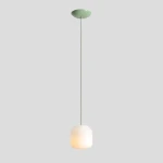 Lampa wisząca Flask Sage D18 w kolorze szałwii, z białym kloszem o kształcie heksagonalnym, zawieszona na cienkim, zielonym przewodzie. Elementy montażowe w kolorze szałwii. Prosta, elegancka forma, idealna do nowoczesnych wnętrz.