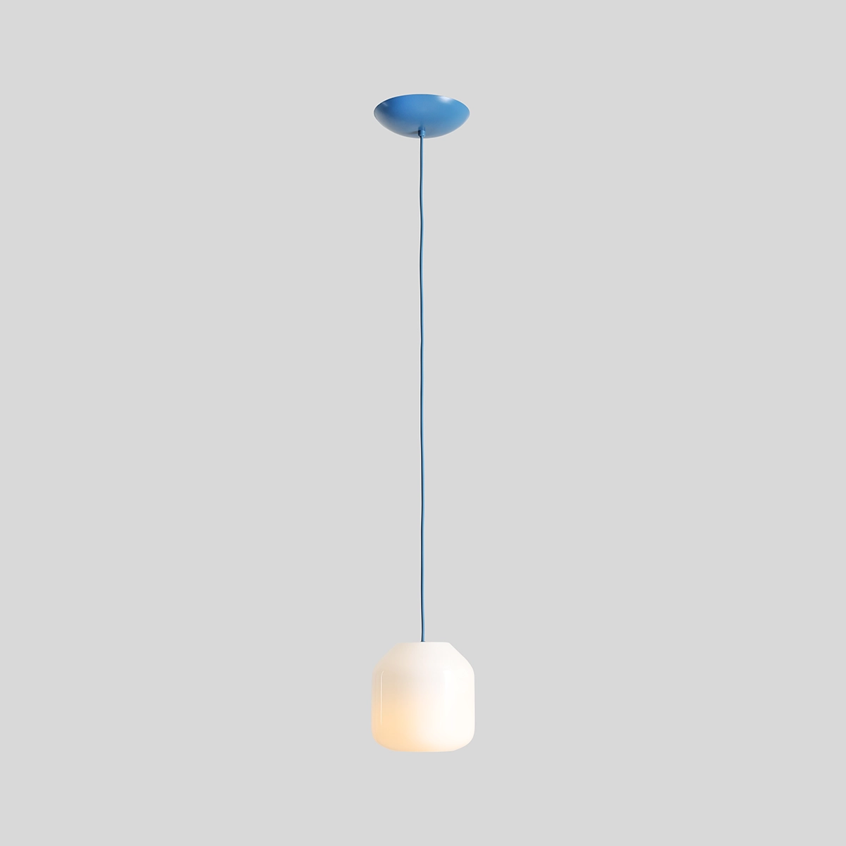 Lampa wisząca Flask Sapphire D18 z kloszem w kształcie sześcianu, w kolorze białym, zawieszona na niebieskim przewodzie. U góry znajduje się okrągła niebieska podsufitka. Produkt przeznaczony na źródło światła E14.