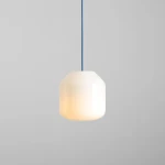 Lampa wisząca Flask Sapphire D18 z białym, zaokrąglonym kloszem i niebieskim przewodem. Klosz emituje ciepłe światło, zawieszony w centralnej pozycji na szarym tle. Idealna do nowoczesnych wnętrz.