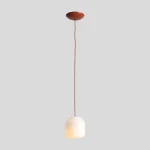 Lampa wisząca Flask Terra D18 z kloszem w kształcie sześcianu, wykonana z białego szkła, zawieszona na ceglanej oprawie. Długa, gładka linka w kolorze ceglastym. Klosz emitujący ciepłe światło, montowany na suficie.