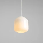 Lampa wisząca Flask Cotton D18 w kremowym kolorze, z przeźroczystym kloszem o zaokrąglonym kształcie. Ujęcie z góry, zawieszona na cienkim, białym przewodzie, emitująca ciepłe światło. Tło szare, minimalistyczne.