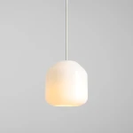 Kremowa lampa wisząca Flask Cotton D18 z jedną oprawą E14, o zaokrąglonym kształcie. Wisi na cienkim, białym przewodzie, emitując ciepłe światło. Tło w odcieniu szarości, co podkreśla minimalistyczny design.