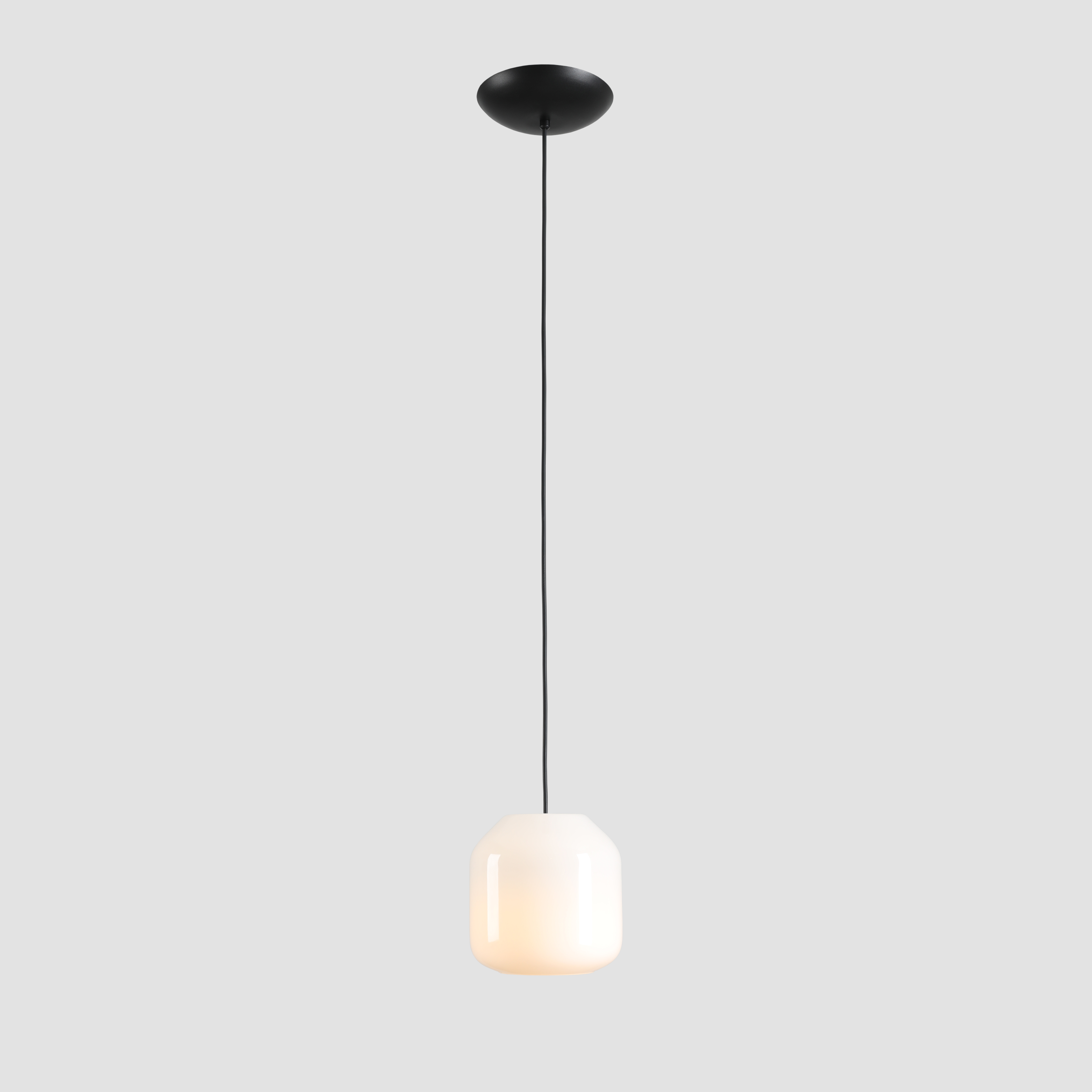 Lampa wisząca Flask Orchid D18 z kloszem w kolorze białym, o matowej fakturze, zawieszona na czarnym przewodzie. Kształt klosza przypomina sześcian z zaokrąglonymi krawędziami. Montaż sufitowy z płaską, okrągłą podstawą.