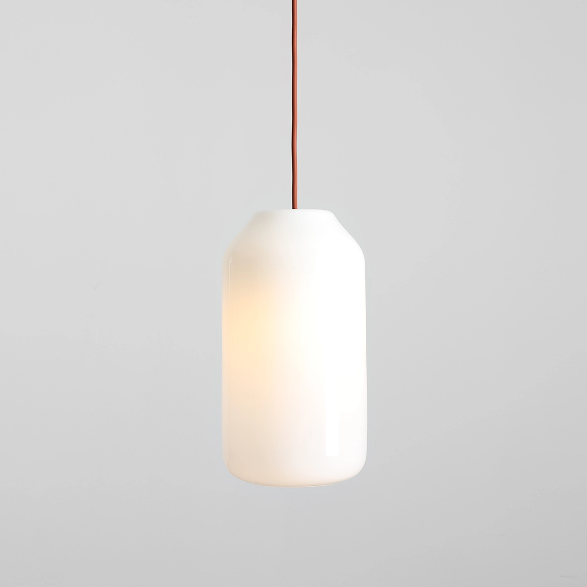 Lampa wisząca Flask Terra D19 w kształcie cylindrycznym, wykonana z białego szkła, zawieszona na ceglanej, teksturowanej przewodach. Źródło światła E27, delikatne podświetlenie. Ujęcie frontalne na jasnym tle.