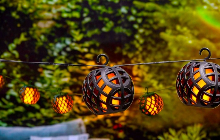 Girlanda ogrodowa solarna Glovi z 20 LED-ami, długość 4 m, czarna. Lampiony w kształcie kul z siatkową osłoną emitują ciepłe światło, zawieszone na cienkim przewodzie, w otoczeniu zieleni, tworząc przytulną atmosferę.