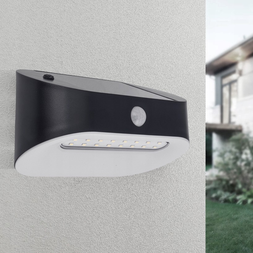 Czarny kinkiet elewacyjny Uran LED z czujnikiem ruchu i zmierzchu, montowany na ścianie. Produkt ma nowoczesny kształt, z widocznymi diodami LED oraz czujnikiem. Tło jest jasne, co podkreśla jego design.