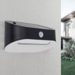 Czarny kinkiet elewacyjny Uran LED z czujnikiem ruchu i zmierzchu, montowany na ścianie. Produkt ma nowoczesny kształt, z widocznymi diodami LED oraz czujnikiem. Tło jest jasne, co podkreśla jego design.