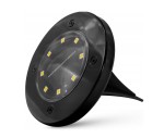 Czarna lampa solarna ogrodowa Terra wbijana, okrągła, z przezroczystą osłoną i sześcioma diodami LED. Pozycjonowana w pionie, z widocznymi śrubami na obrzeżu. Idealna do oświetlenia ścieżek w ogrodzie.